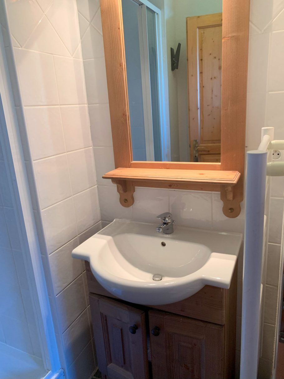 Vasque en salle de bain avec miroir au-dessus et meuble en bois.