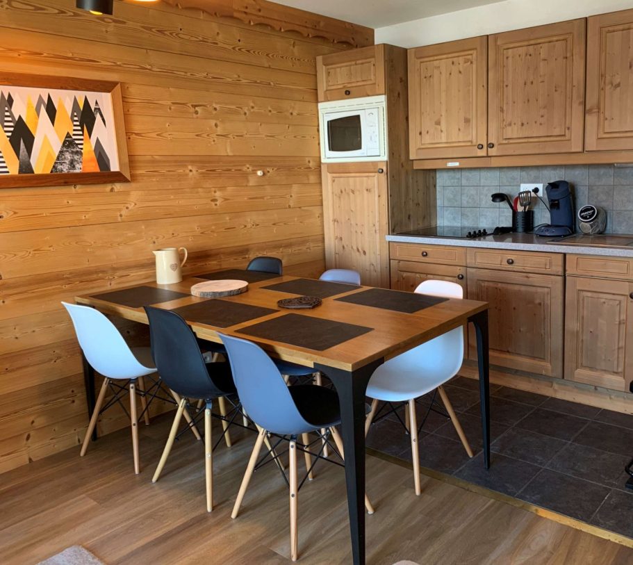 Cuisine en bois avec une table et des chaises modernes, espace lumineux et accueillant.
