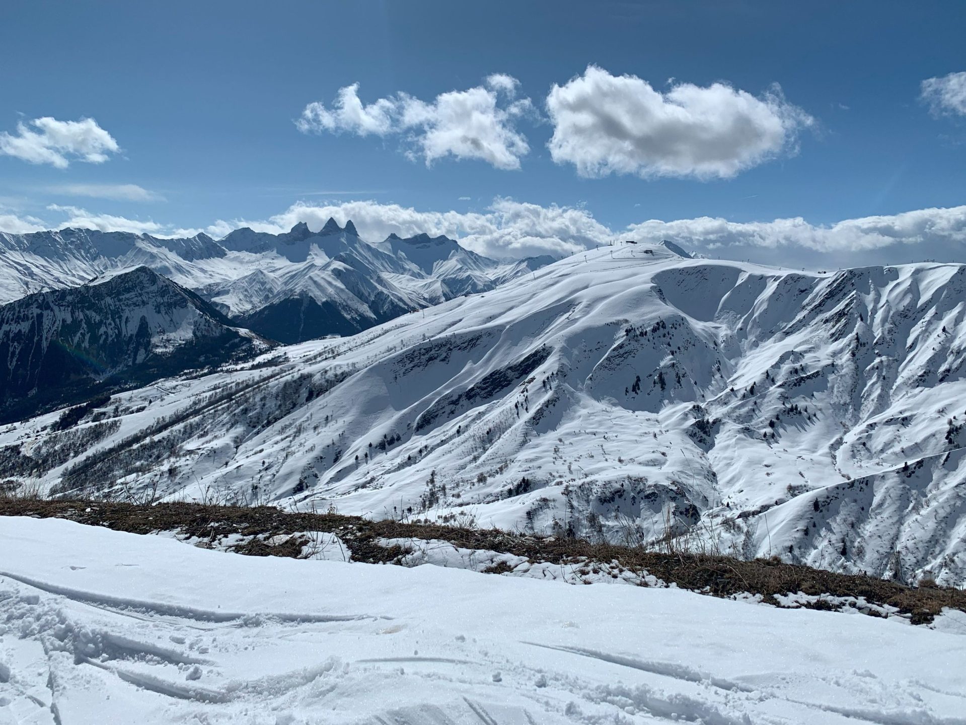 Paysage montagneux enneigé avec des sommets lumineux sous un ciel partiellement nuageux.