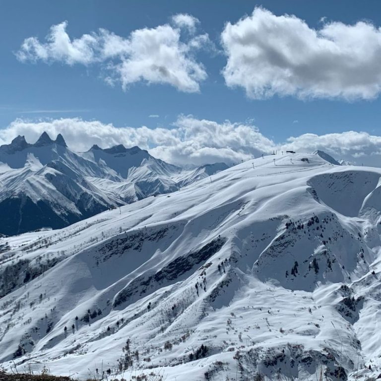 Paysage de montagnes enneigées sous un ciel partiellement nuageux.