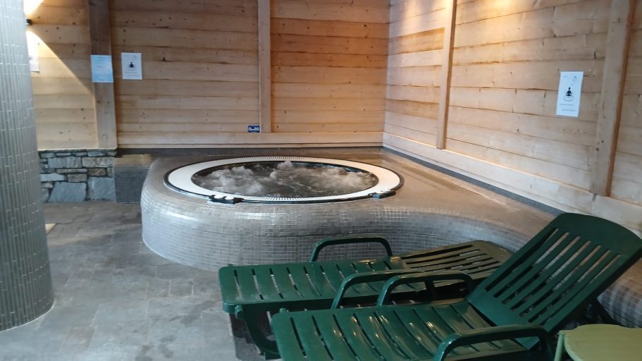 Bain à remous dans une pièce en bois avec des chaises longues à côté.